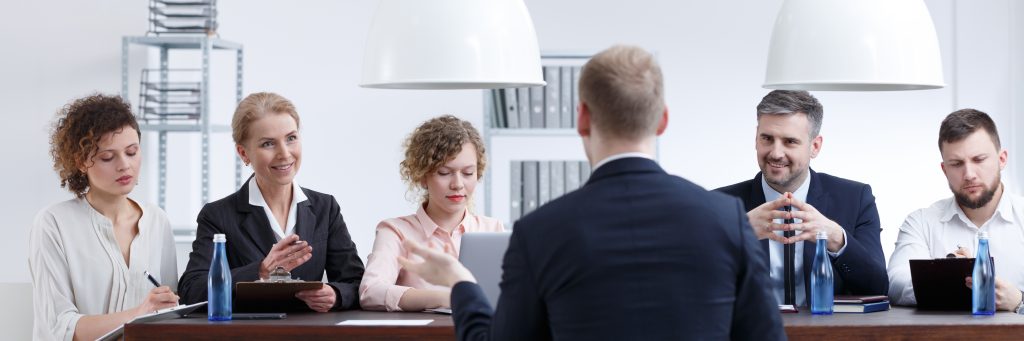 Image of men and women interviewing a job candidate in an office setting.